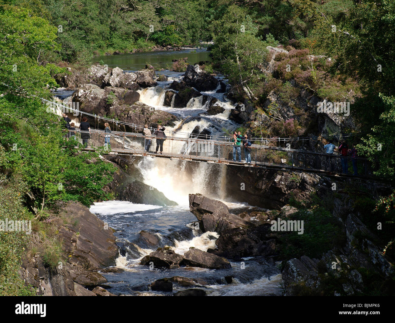 People on suspension bridge in Rogie falls on the blackwater river near Strampeffer Stock Photo