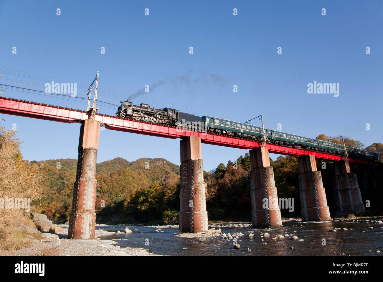 Steam train crossing railway bridge Stock Photo