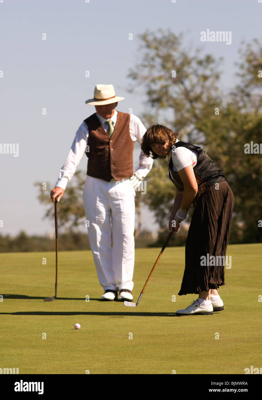 A man and a women dressed in 1900-era costumes taking part in a hickory golf tournament. Stock Photo
