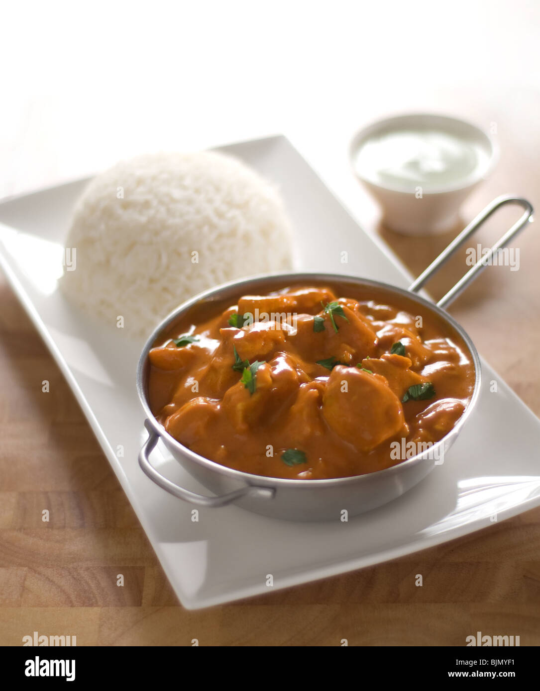 A serving of the Indian food Butter Chicken presented in single serve pan with basmati rice and
