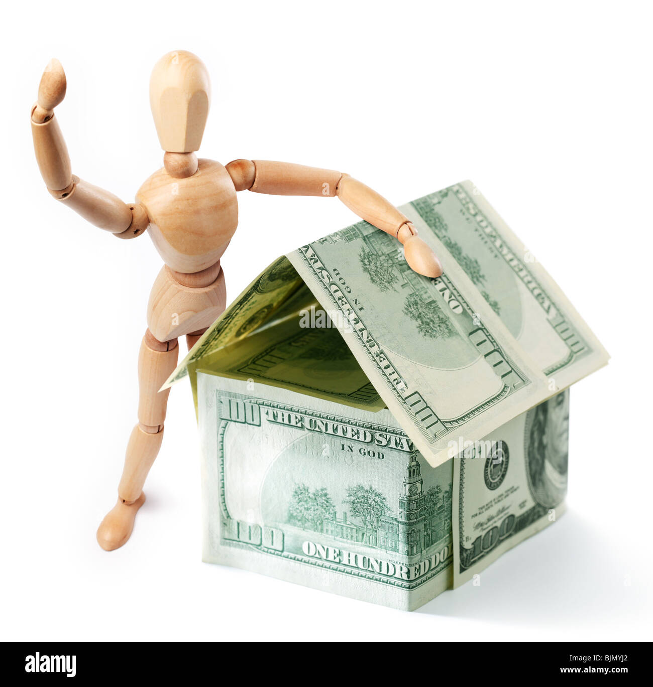 Wooden man standing next to a dollar house Stock Photo