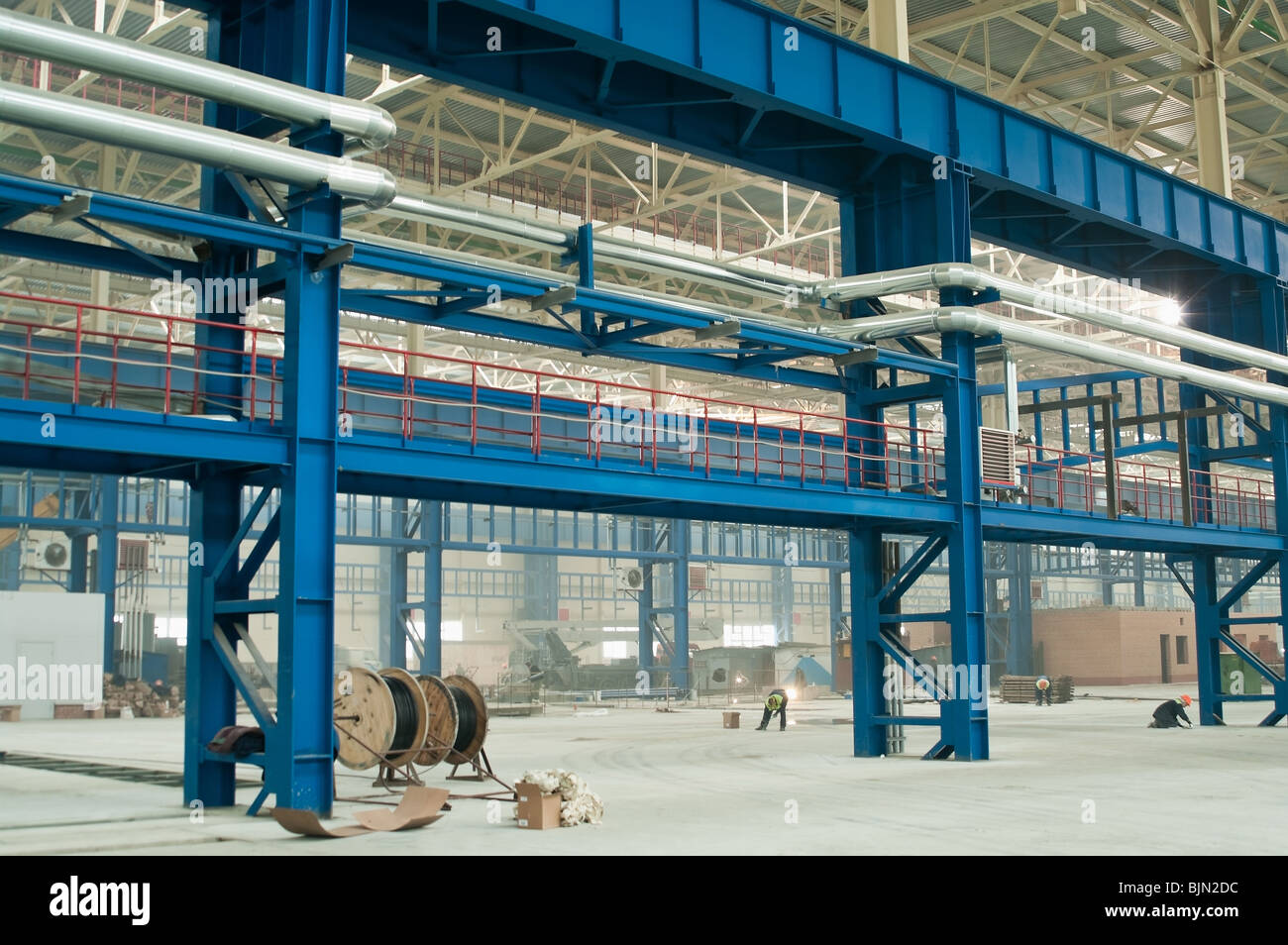 Factory heat supply network between consumers works by above-ground pipelines on the wall and by columns. Stock Photo