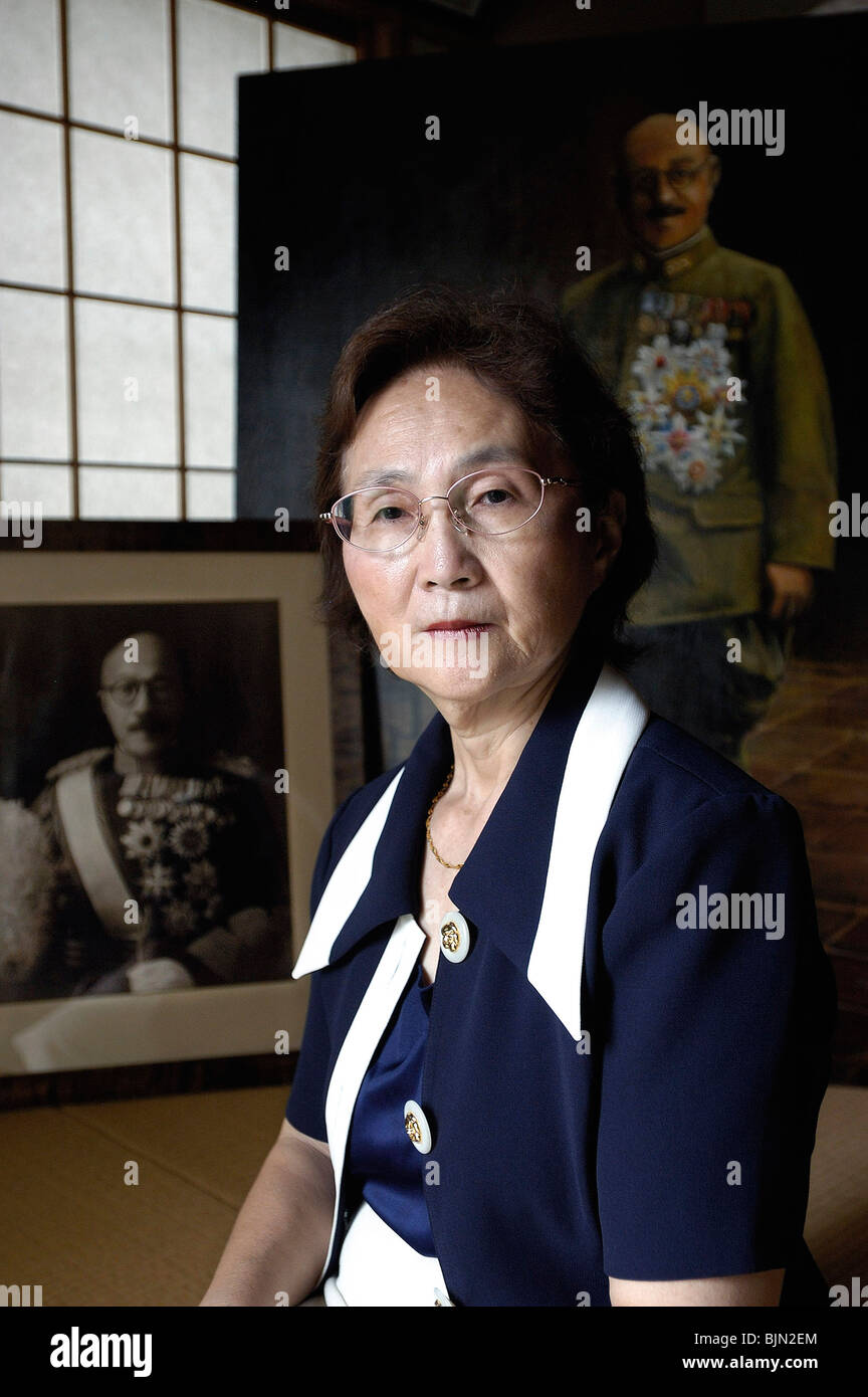 Yuko Tojo, granddaughter of wartime leader, Gen. Hideki Tojo, poses in front of a portrait and photo of her grandfather in Tokyo Stock Photo
