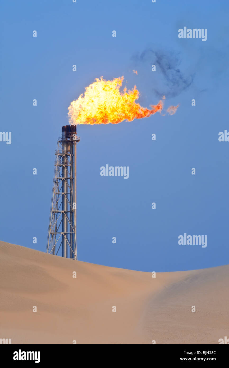 A flare stack burning off excess gas at an oil refinery in the desert