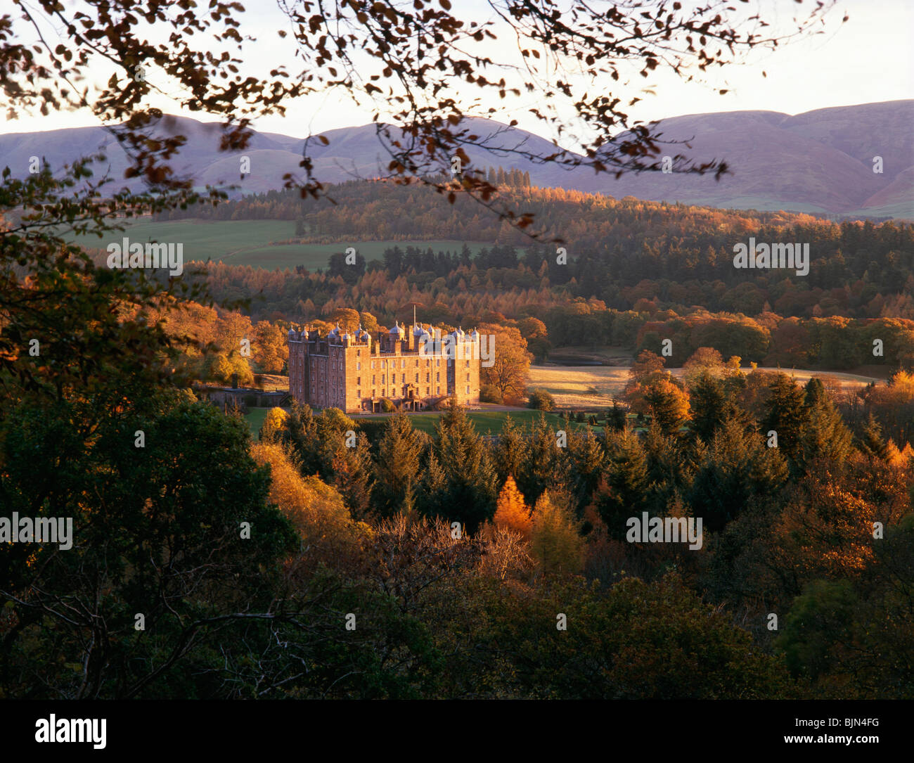 Drumlanrig Castle in a autumn landscape catching the morning sunshine with Lowther Hills behind Scotland UK Stock Photo