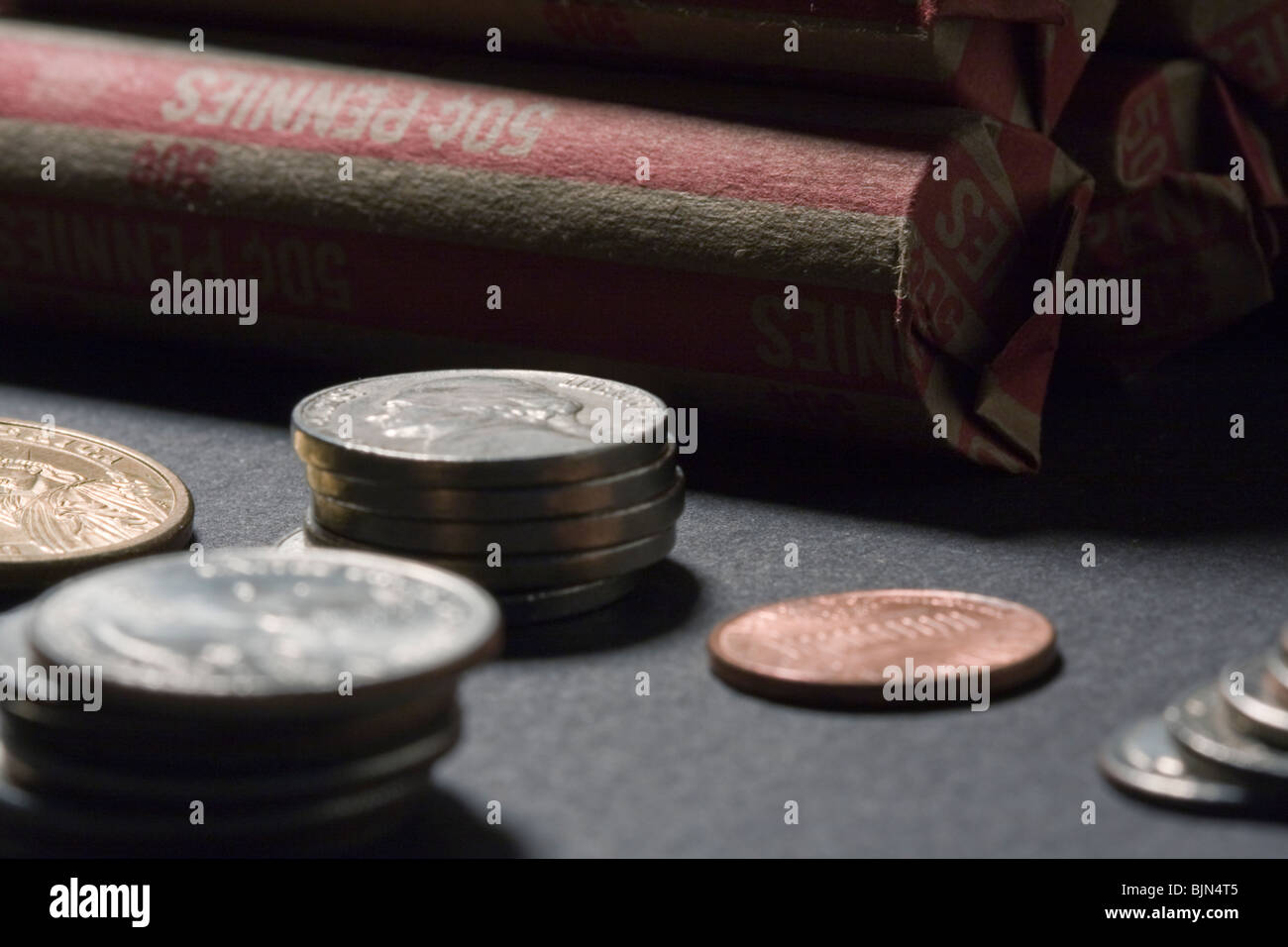 Close Up of Rolled Pennies, Nickels, Dimes, Quarters, Dollars on Black Background. Stock Photo