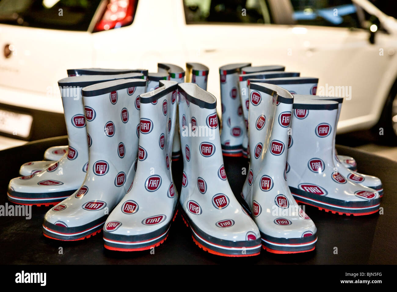 Eight pair of rubber boots with Fiat logos on a table Stock Photo