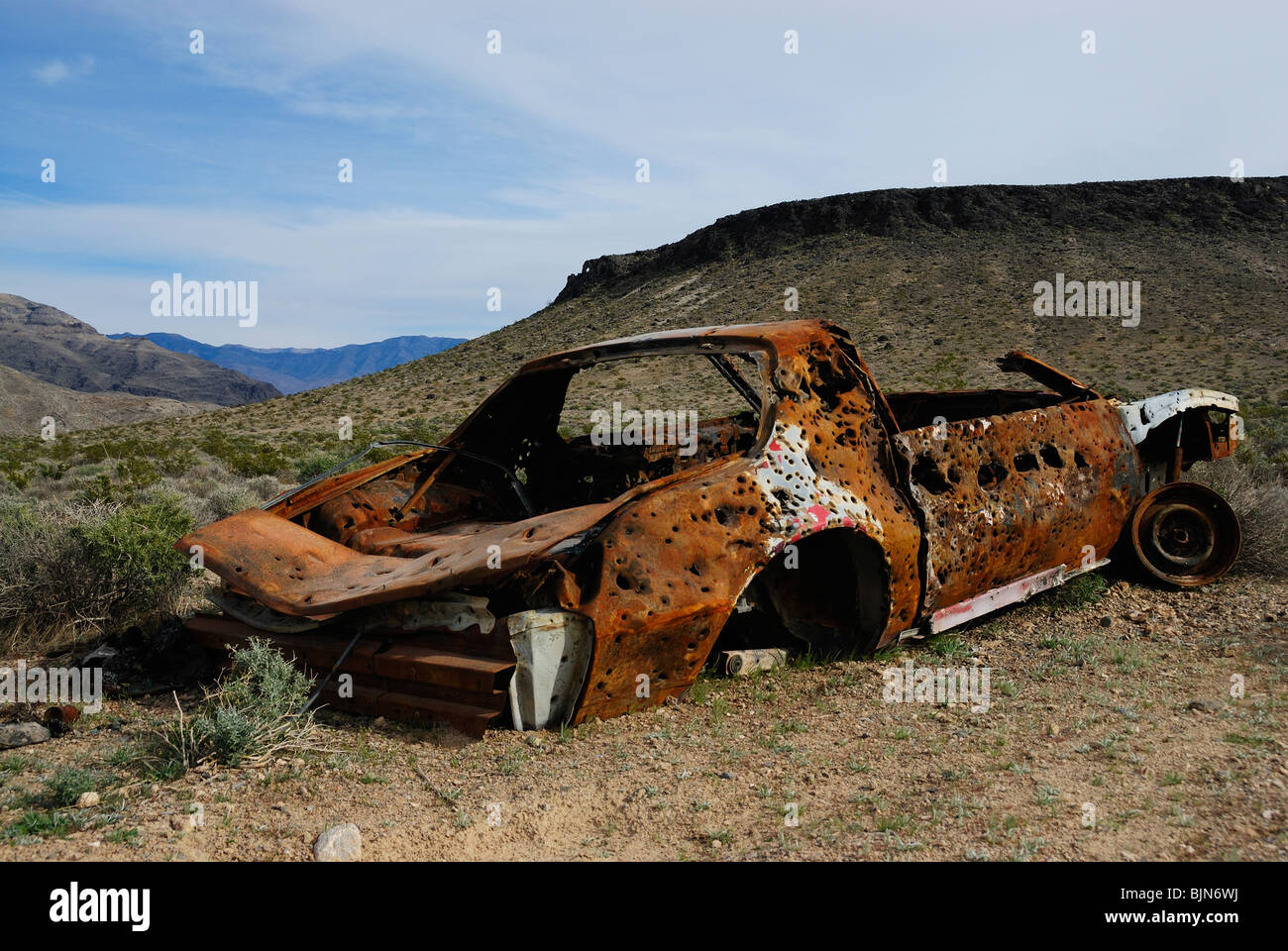Abandoned and rusted car riddled with bullets along a road in Death Valley, California state Stock Photo