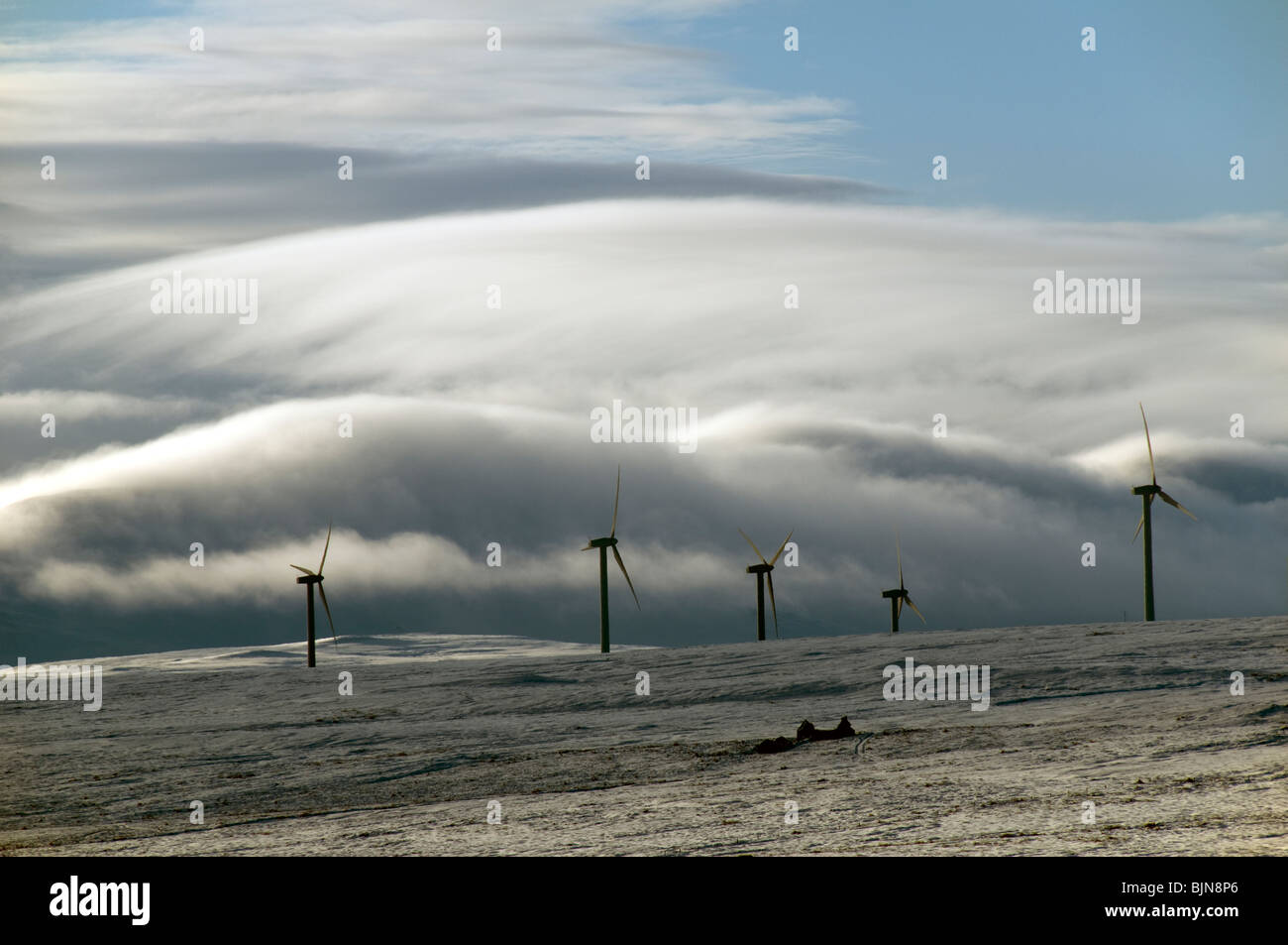 Wind generators on a snow covered hillside in Caithness, Scotland UK.  A mist covered hill behind. Stock Photo