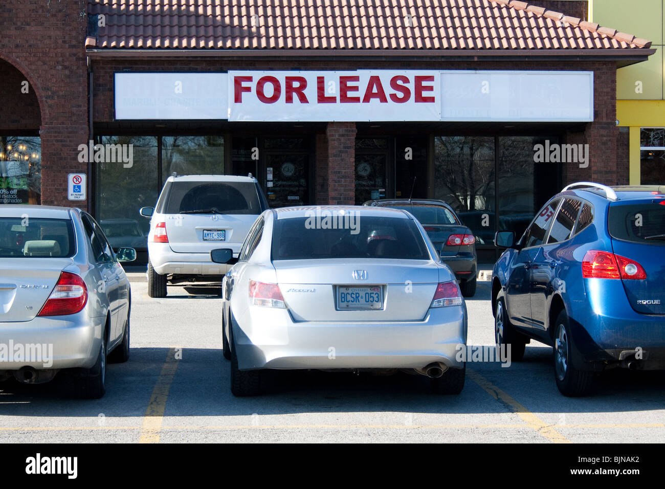 for lease rent sign empty plaza commercial space car front entrance parking lot strip mall real estate rental market greek medit Stock Photo