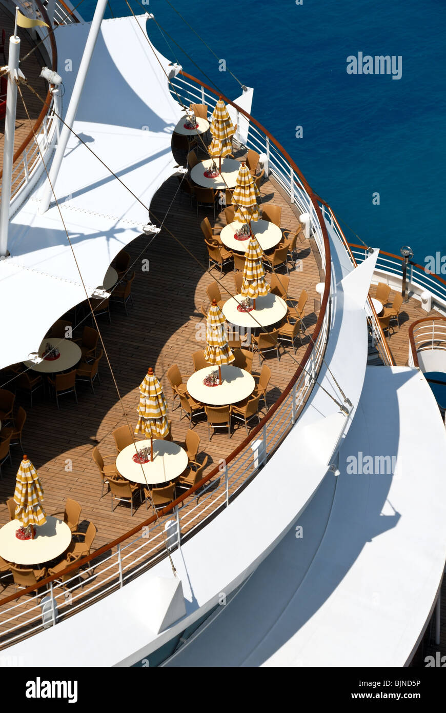 Round patio tables and the rounded curve of the aft of cruise ship AidaVita as it was docked at St. Maarten. Stock Photo