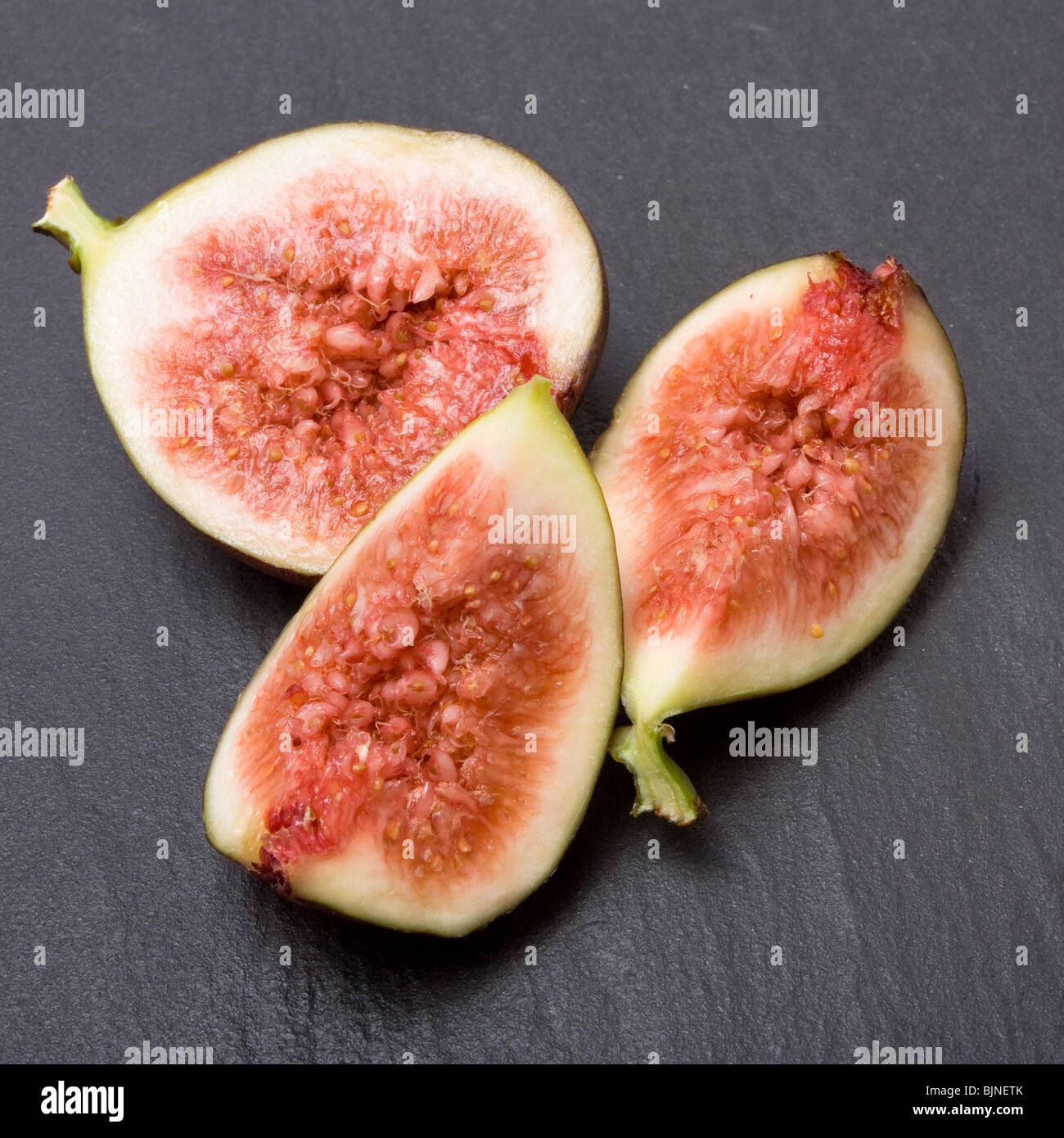 Close up of Sliced ripe figs isolated against dark slate background. Stock Photo
