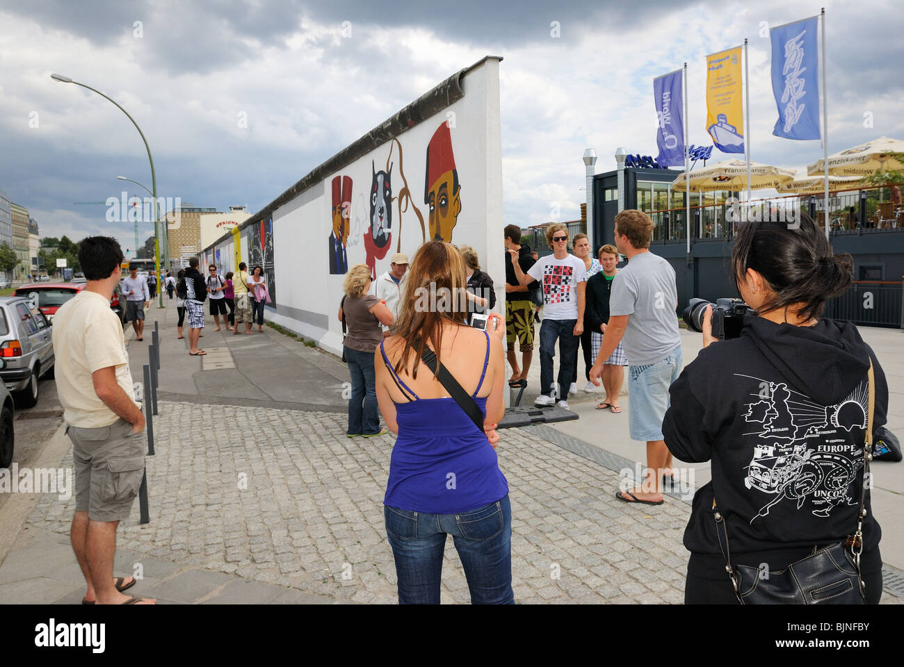 Eastside Gallery, young tourists at the painted, remaining part of the Berlin Wall in Friedrichshain district, Berlin, Germany. Stock Photo