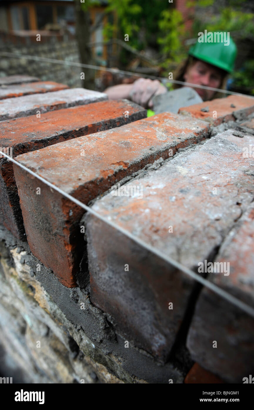 Building of a garden wall with Cotswold stone and reclaimed red bricks UK Stock Photo