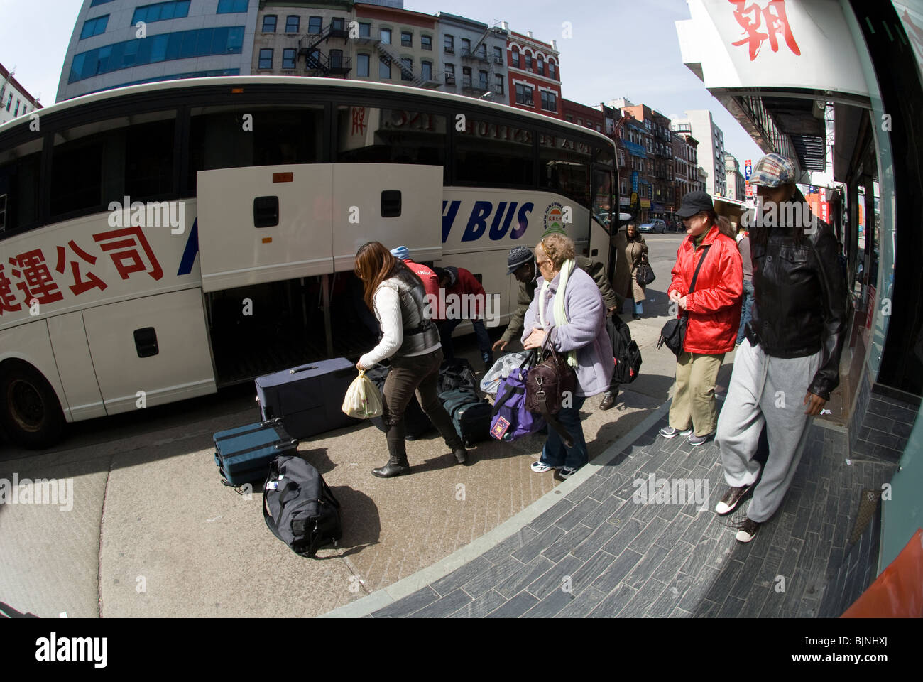 Travelers arrive after traveling on one of the low cost bus services in New York in Chinatown on East Broadway Stock Photo