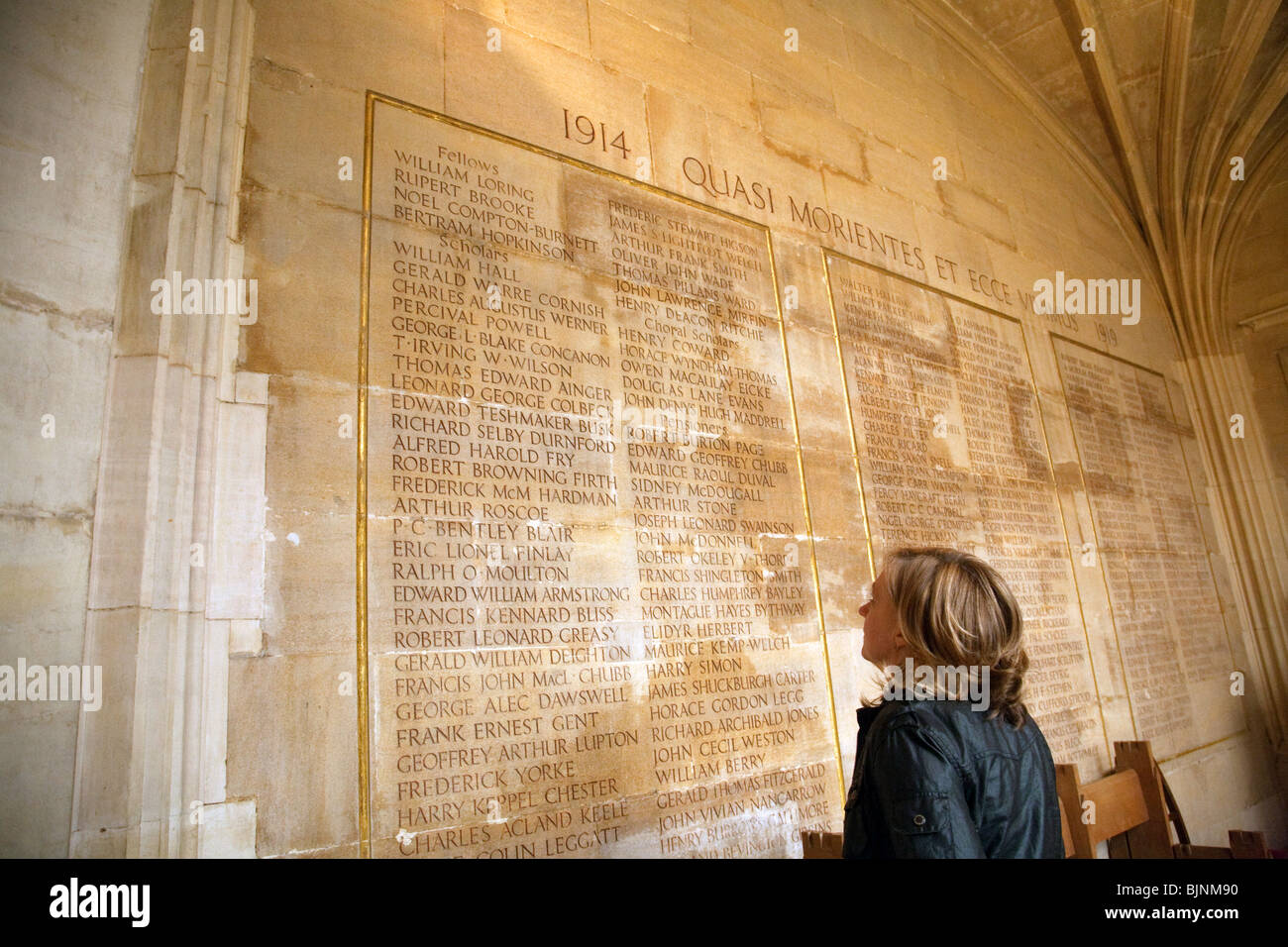 A tourist looking at the names of the dead in World War, including the poet Rupert Brooke, Kings College Chapel, Cambridge UK Stock Photo