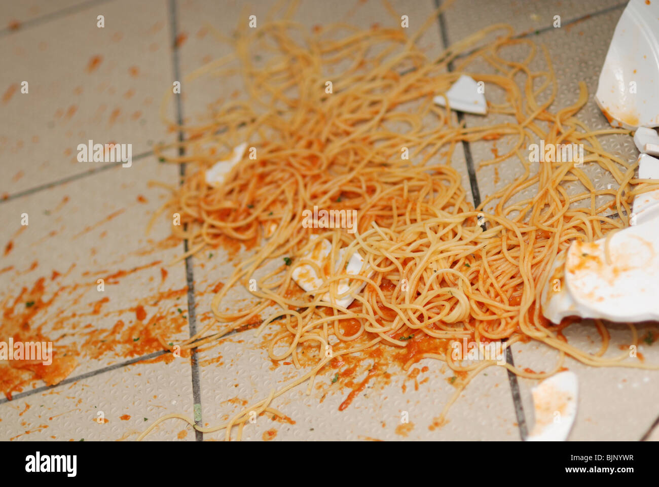Broken plate with spaghetti on the floor of restaurant kitchen Stock