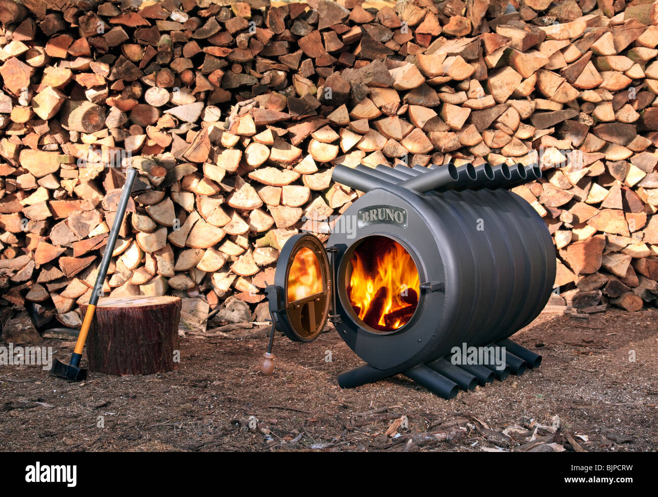 A Large Wood Burning Stove In Front Of A Pile Of Logs With An Axe