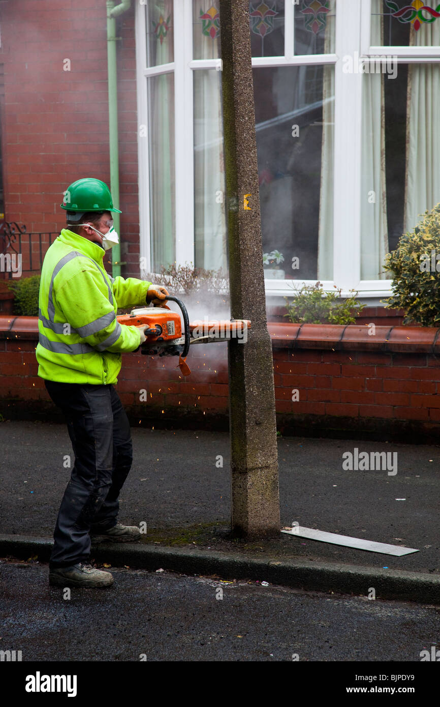 Council worker cutting down a concrete lamp post Stock Photo
