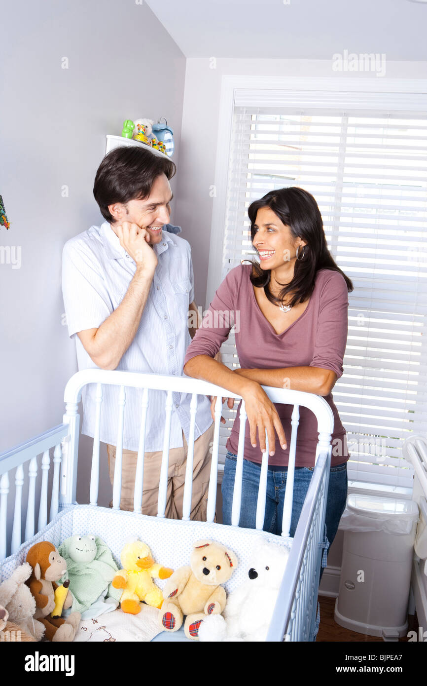 Married couple leaning on baby crib Stock Photo