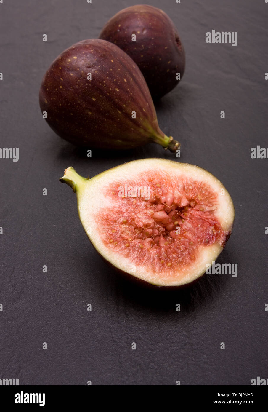 Figs one halved against background of dark grey slate Stock Photo Alamy