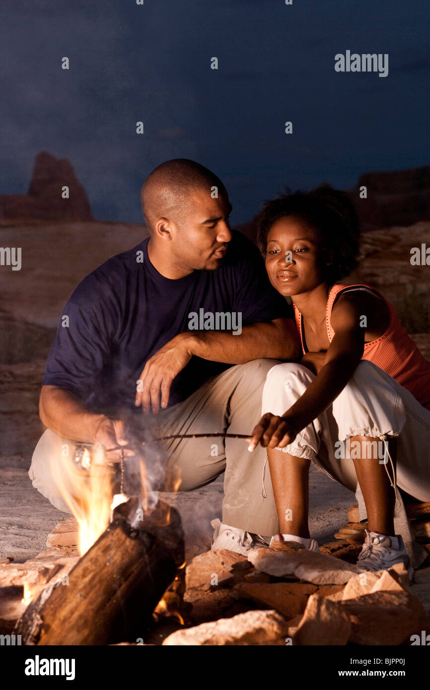 Couple sitting in front of campfire at night Stock Photo - Alamy