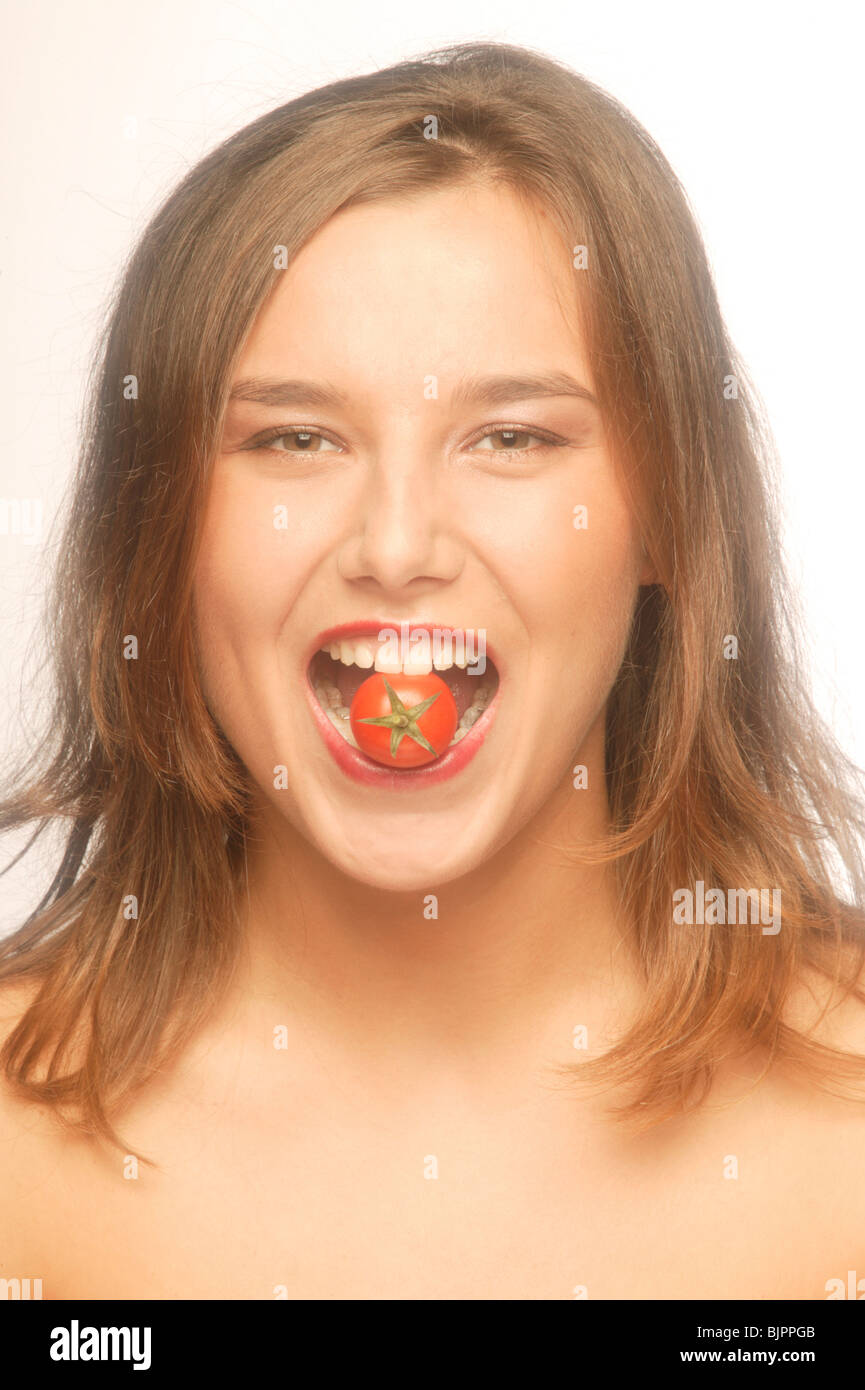 Woman bites into a tomato Stock Photo