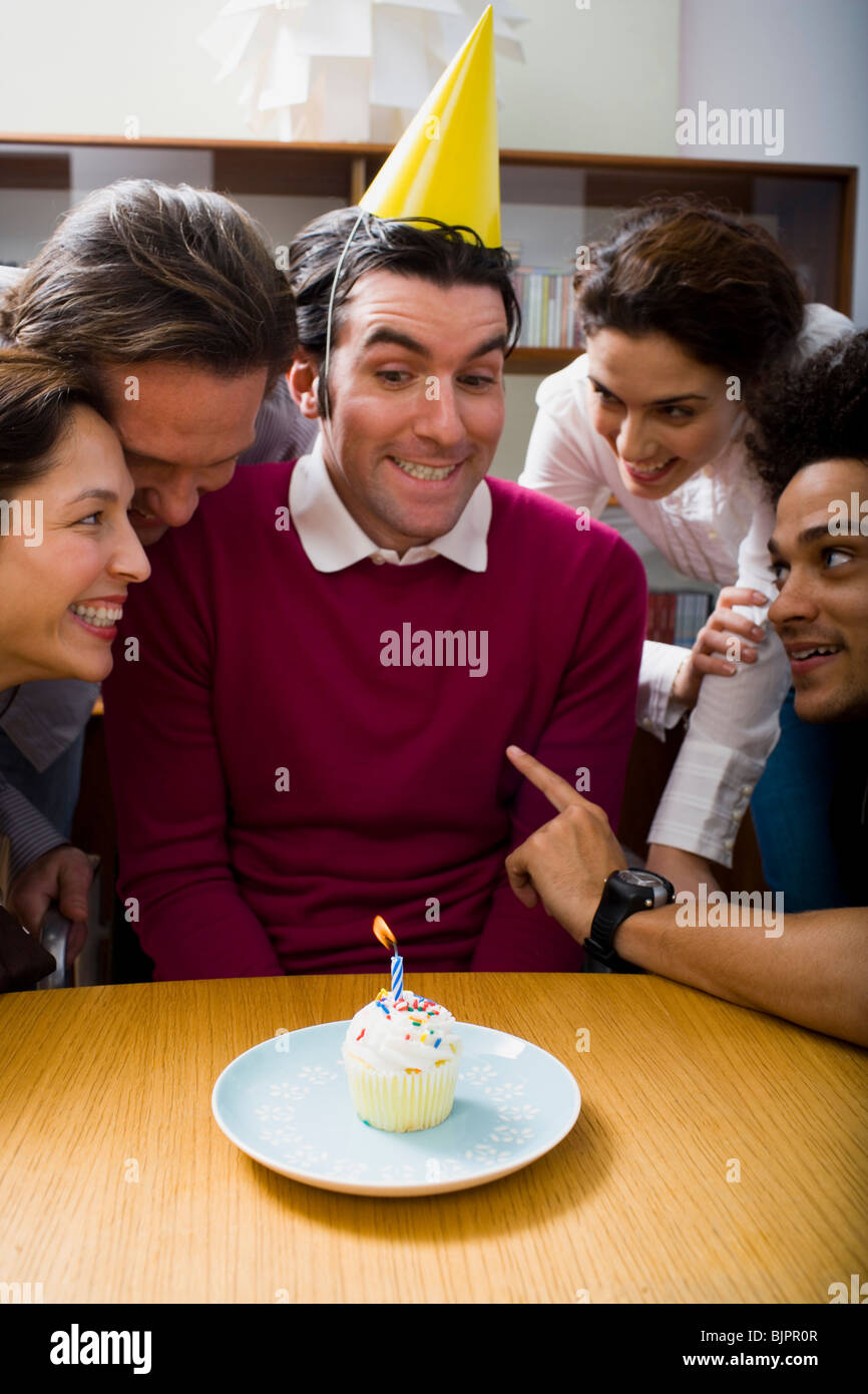 Co-workers around a birthday cupcake Stock Photo