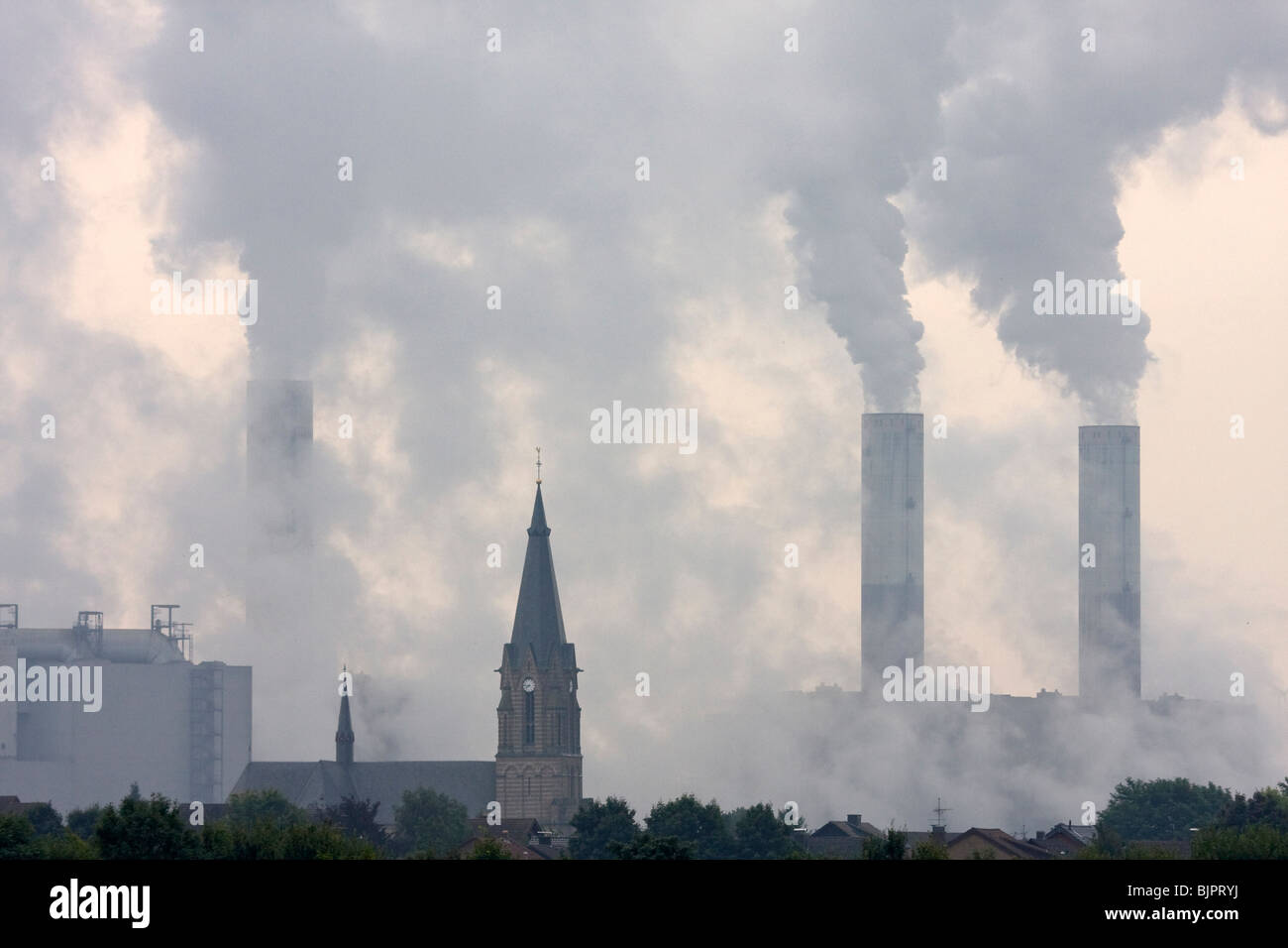 church with smoky power plant Stock Photo