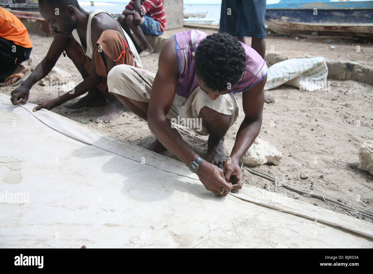 A Swahili man stitching a sail for a dhow ready for the next race
