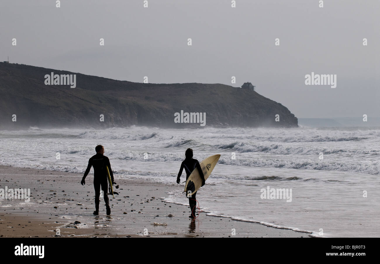 Two surfers walking along Praa Sands in Cornwall. Stock Photo