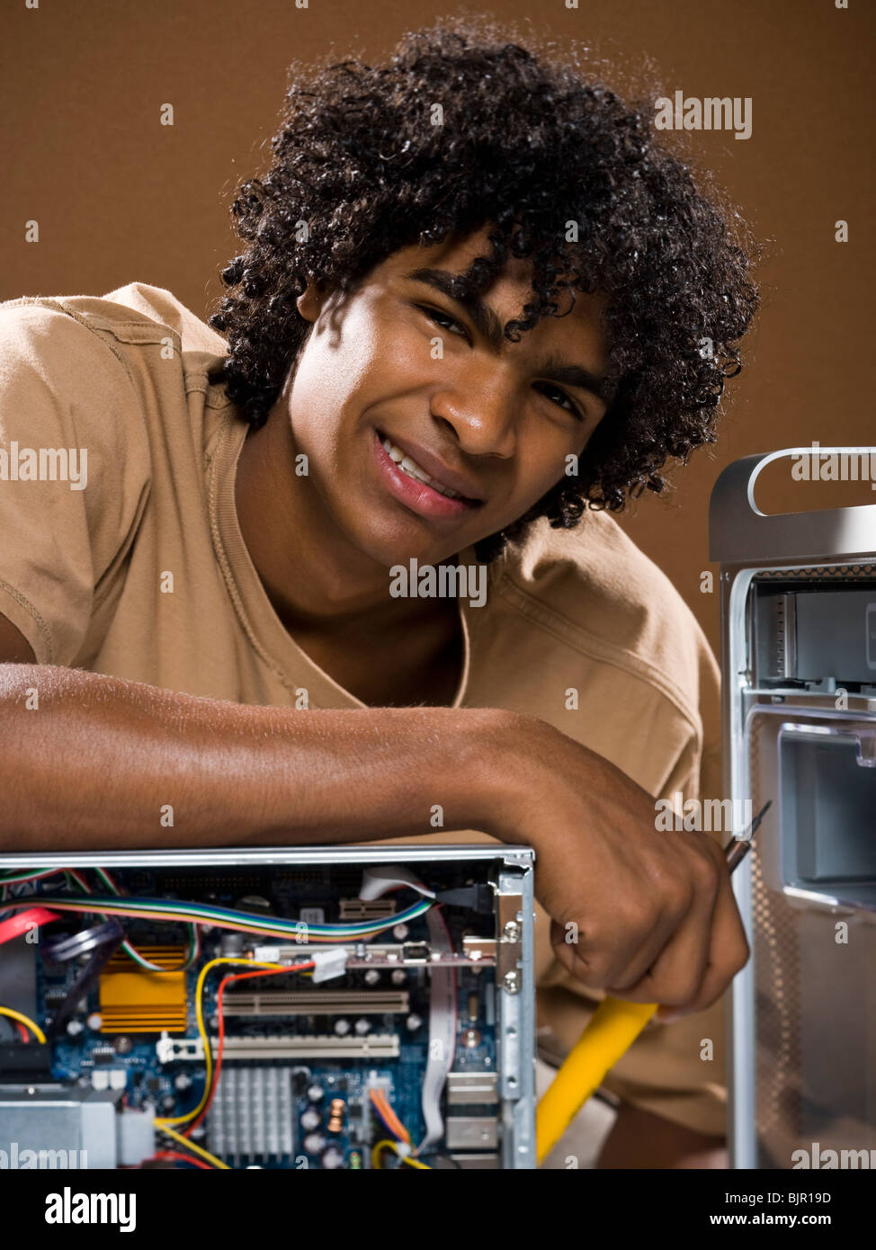 young man in a brown shirt fixing a computer Stock Photo - Alamy