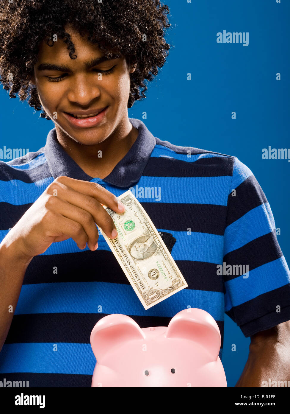 young man putting money in a piggy bank Stock Photo - Alamy