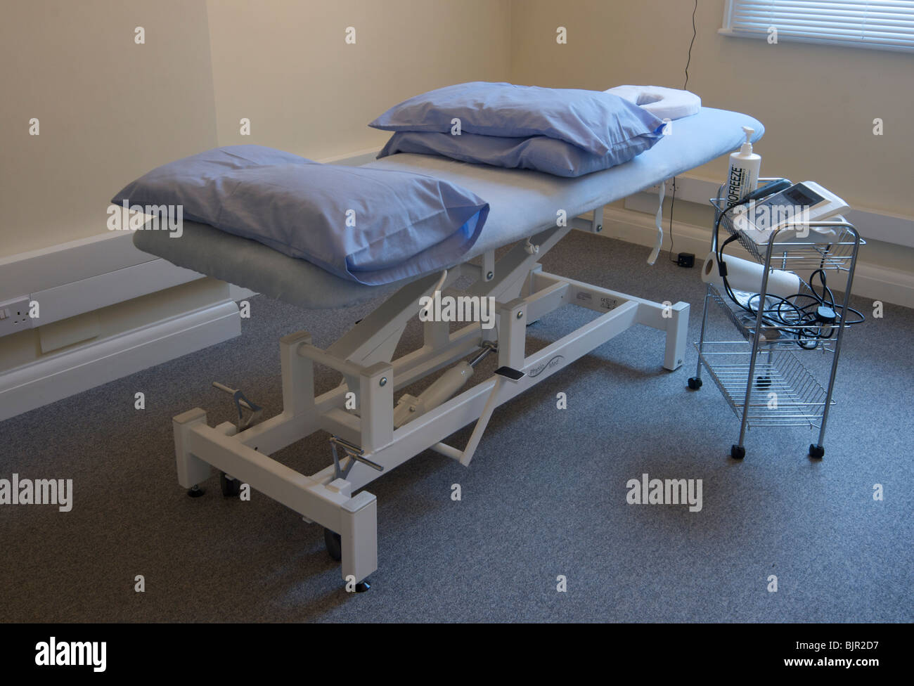 Osteopaths couch with pillows and a trolley containing ultrasound