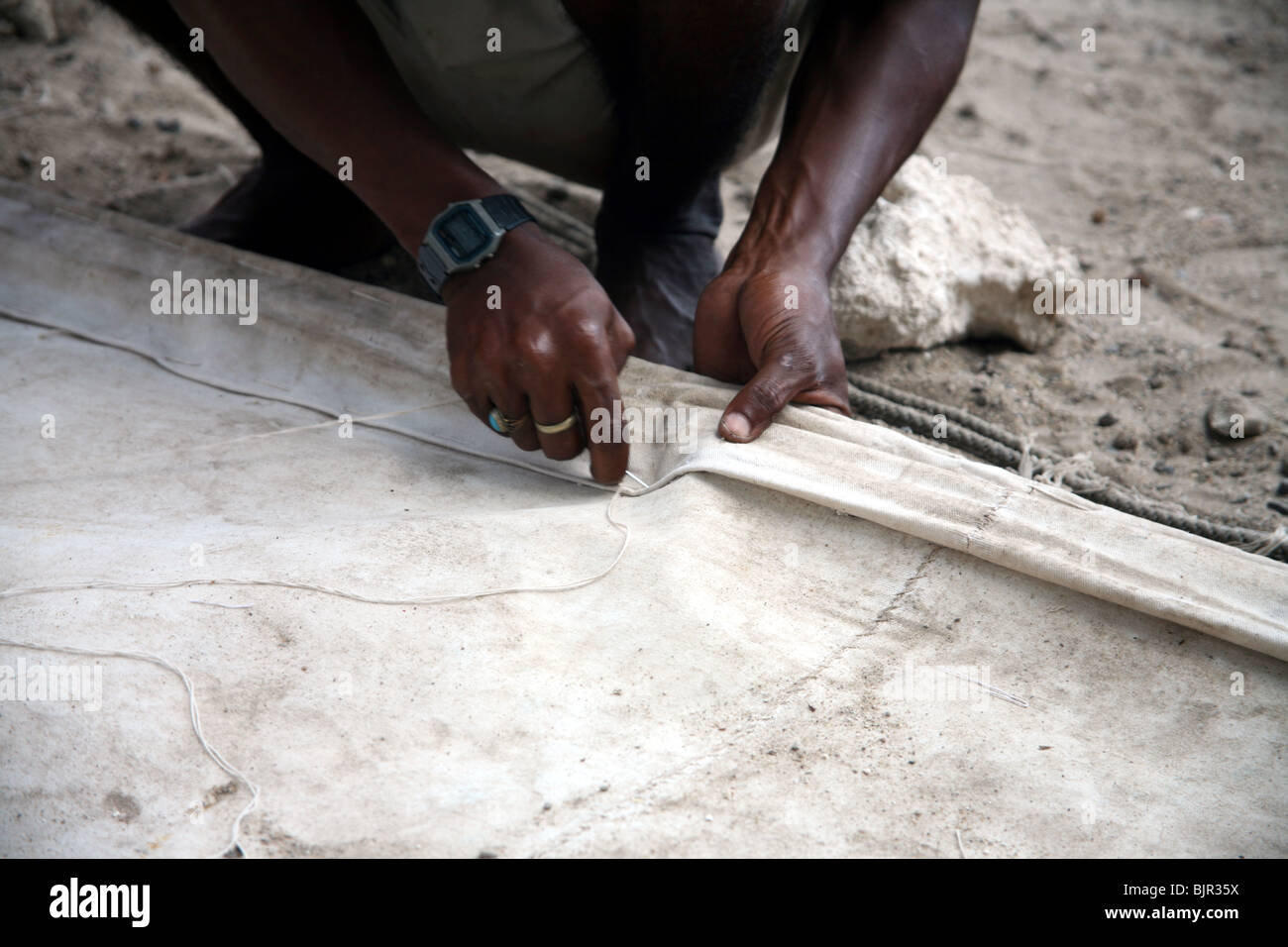 A Swahili man stitching a sail for a dhow ready for the next race