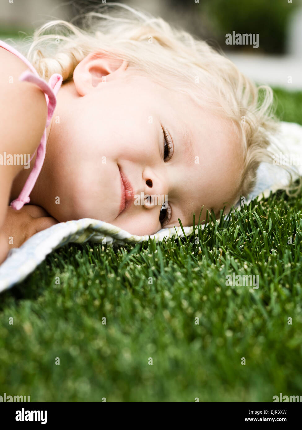 little girl lying on a blanket on the grass Stock Photo Alamy