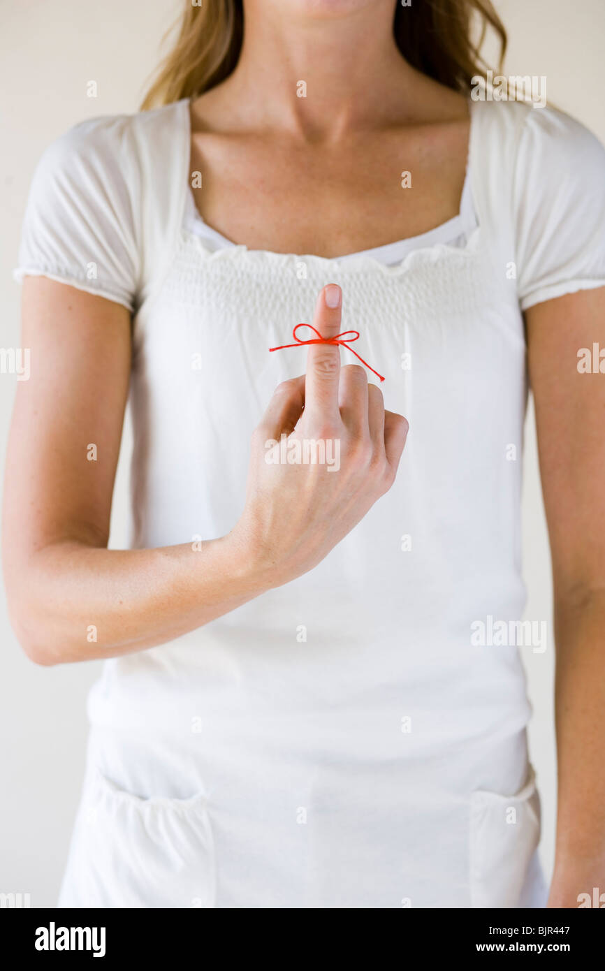 Woman with a red string tied on her finger Stock Photo - Alamy