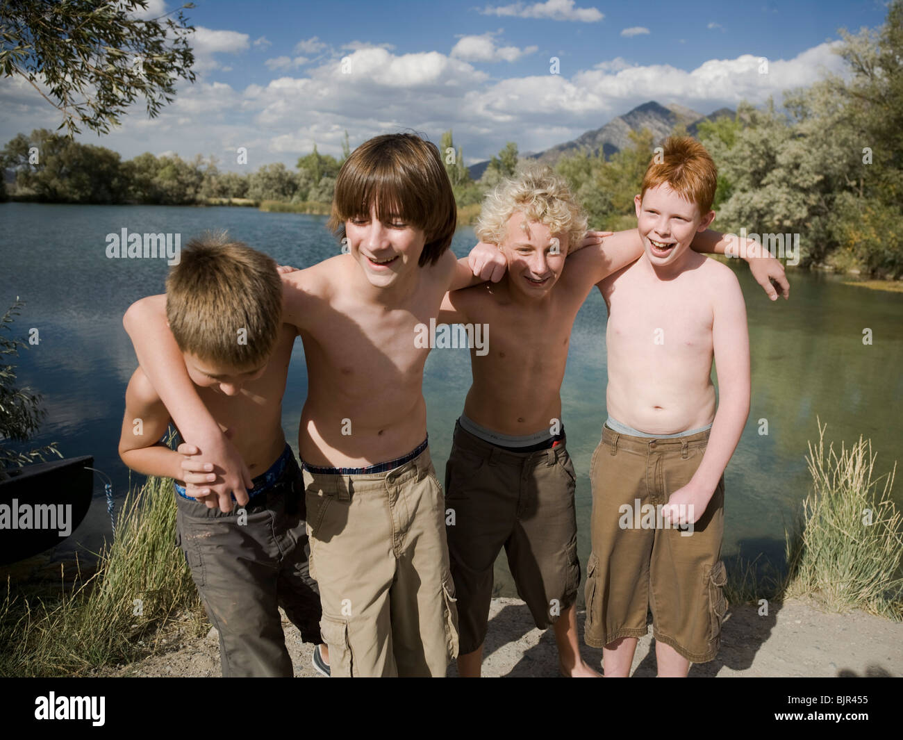 four boys playing by a lake. Stock Photo