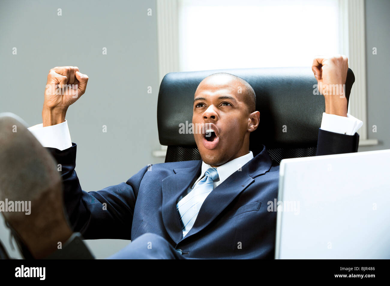 Businessman at desk cheering Stock Photo - Alamy