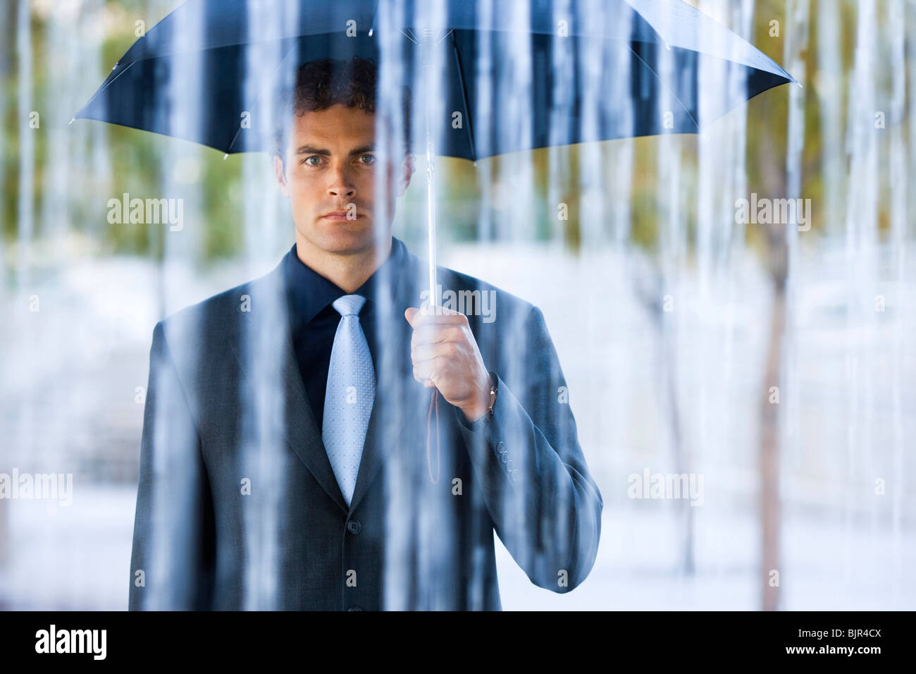 Businessman holding umbrella in rain Stock Photo Alamy