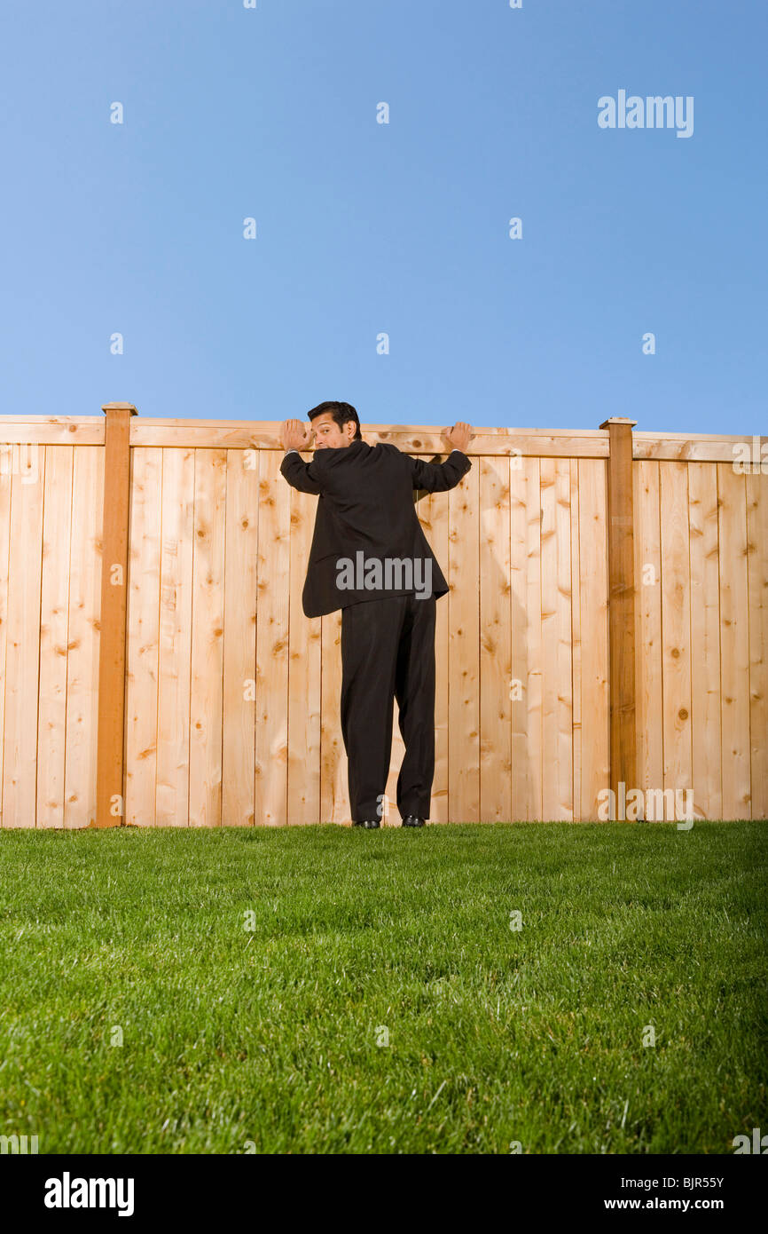 Businessman looking over a wooden fence Stock Photo