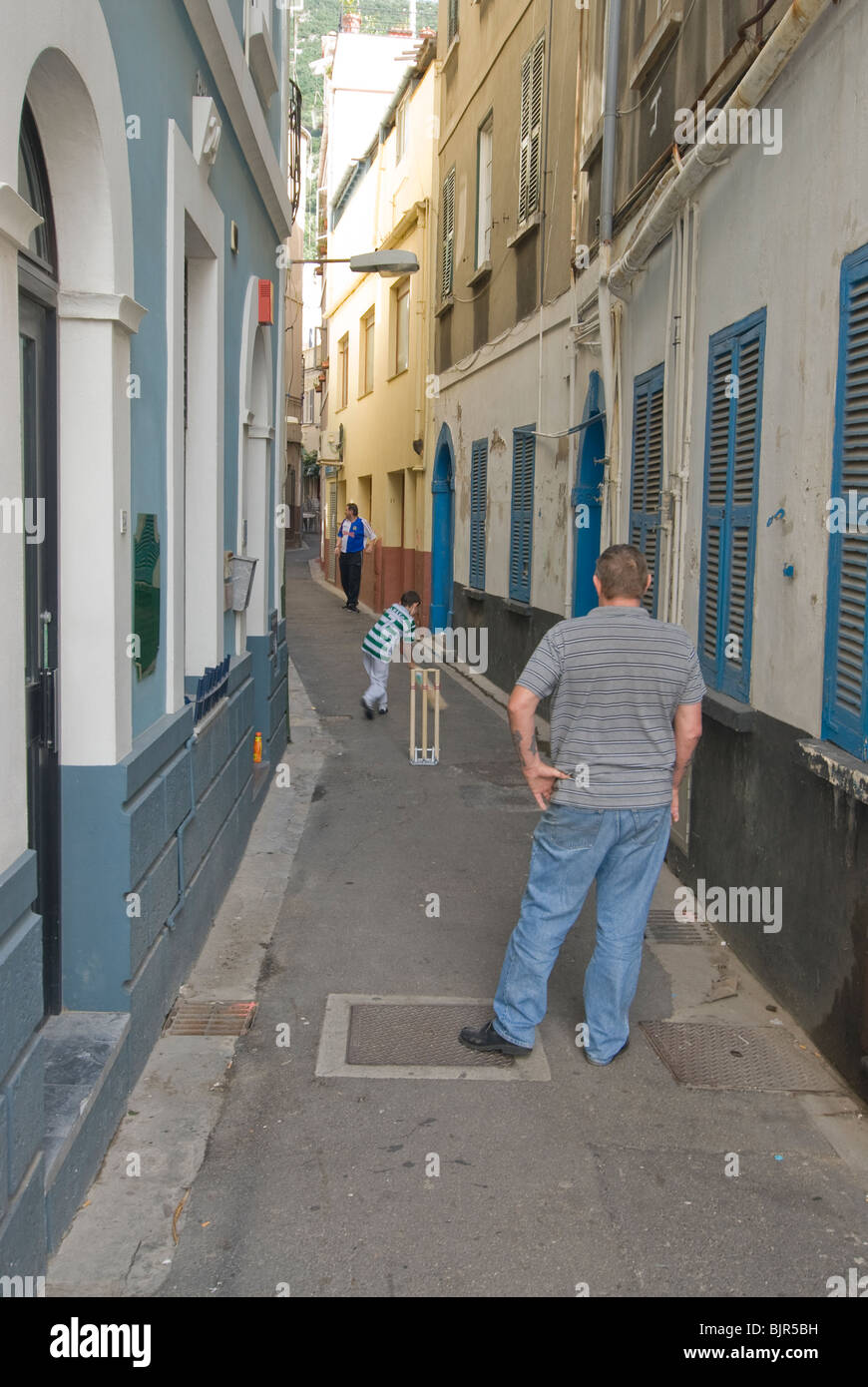 father and son playing cricket in alley Stock Photo