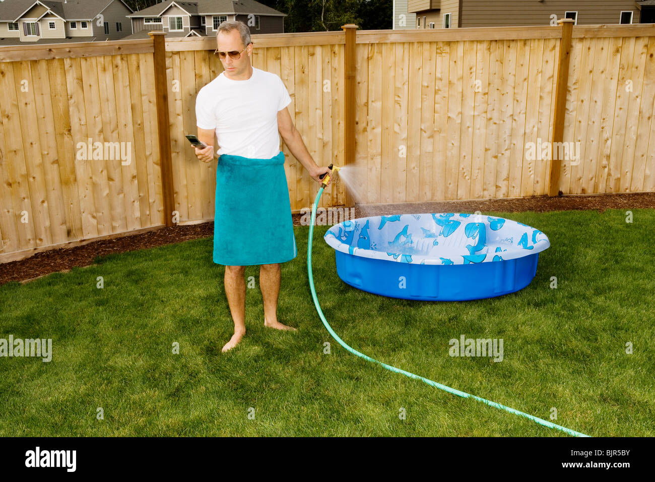 Man in yard with cell phone and hose Stock Photo
