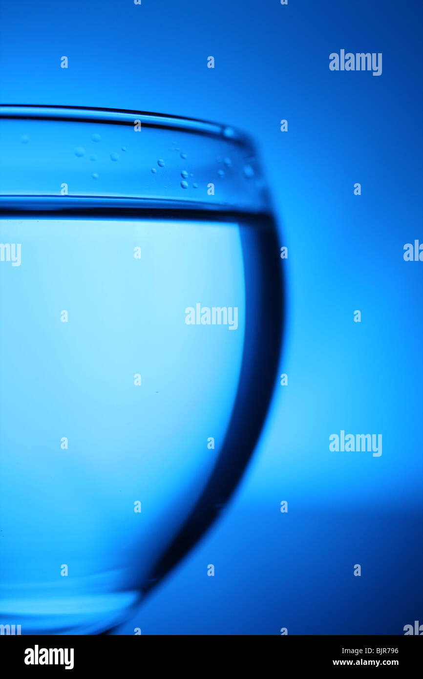 Glass with water on blue background. Stock Photo