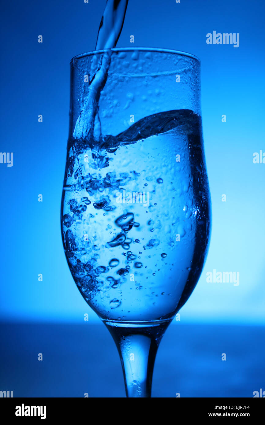 Glass with water on blue background. Stock Photo