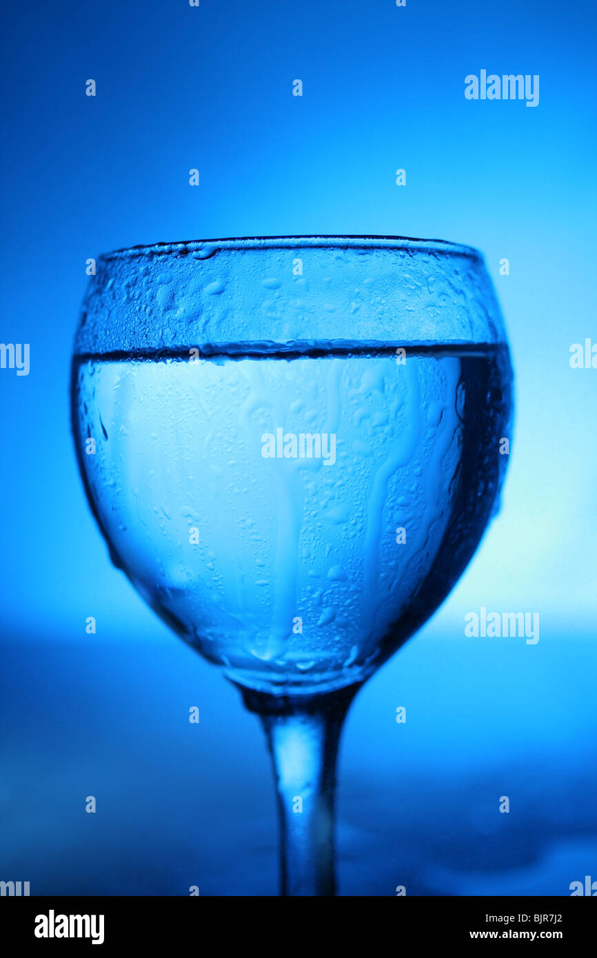 Glass with water on blue background. Stock Photo