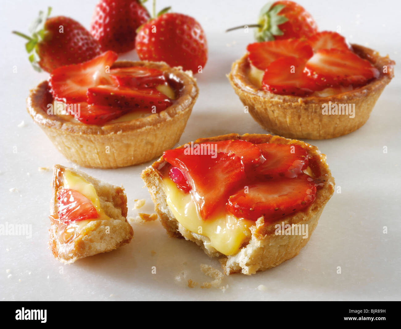 Fresh cooked traditional British strawberry and custard pastry tarts on a white background. Stock Photo