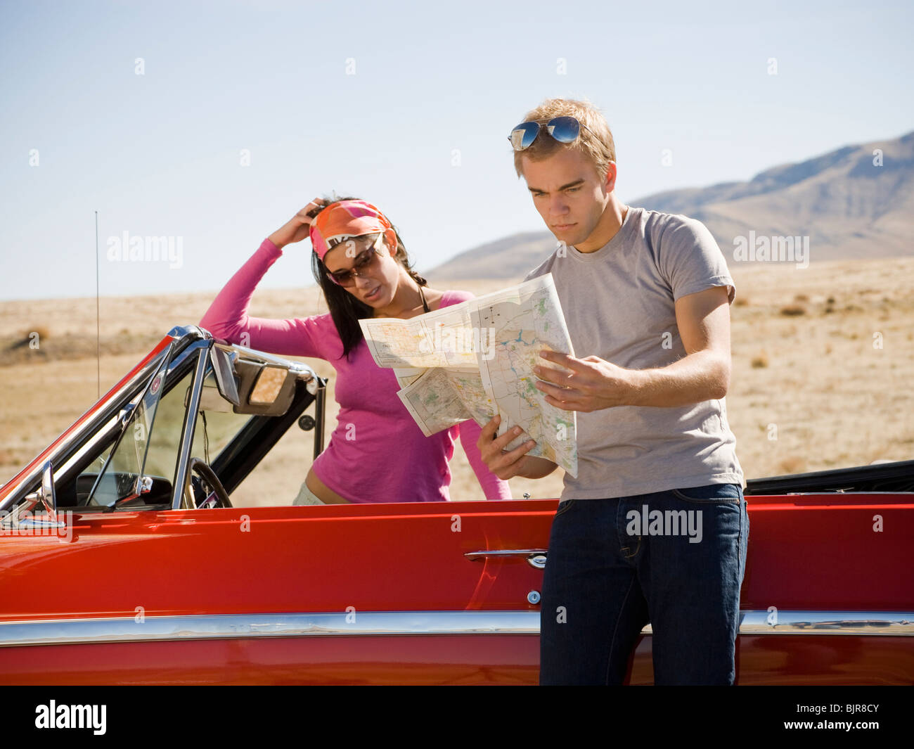 man and woman next to a red convertible Stock Photo