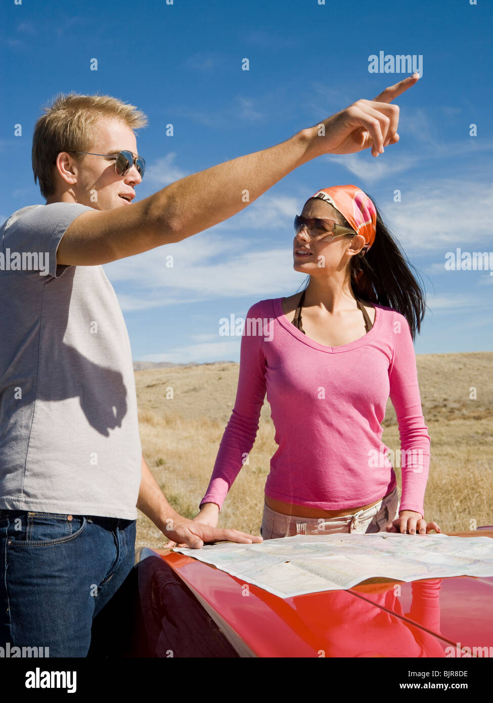 man and woman next to a red convertible Stock Photo