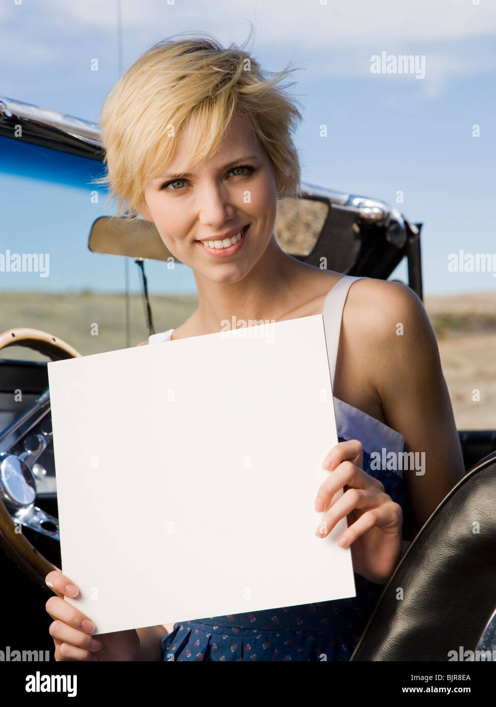 woman in a car with a blank sign Stock Photo